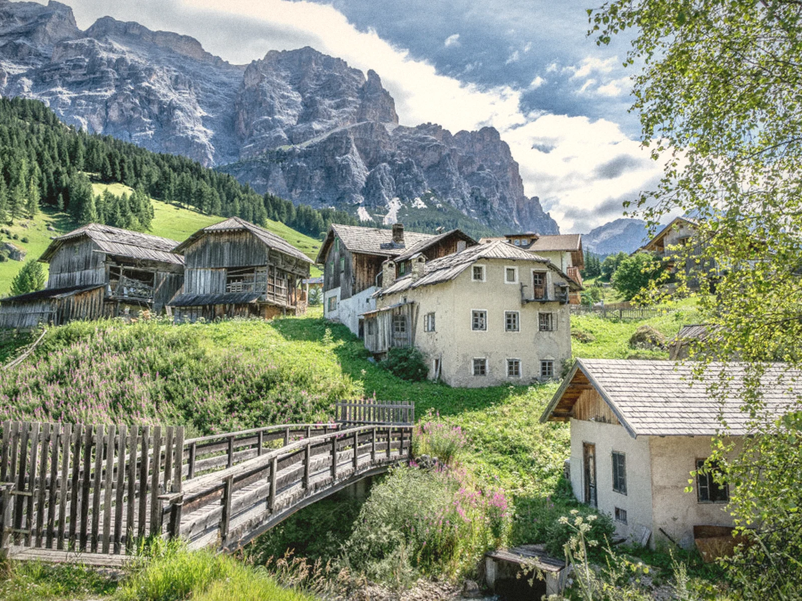 The village of San Cassiano among green meadows and Dolomite peaks
