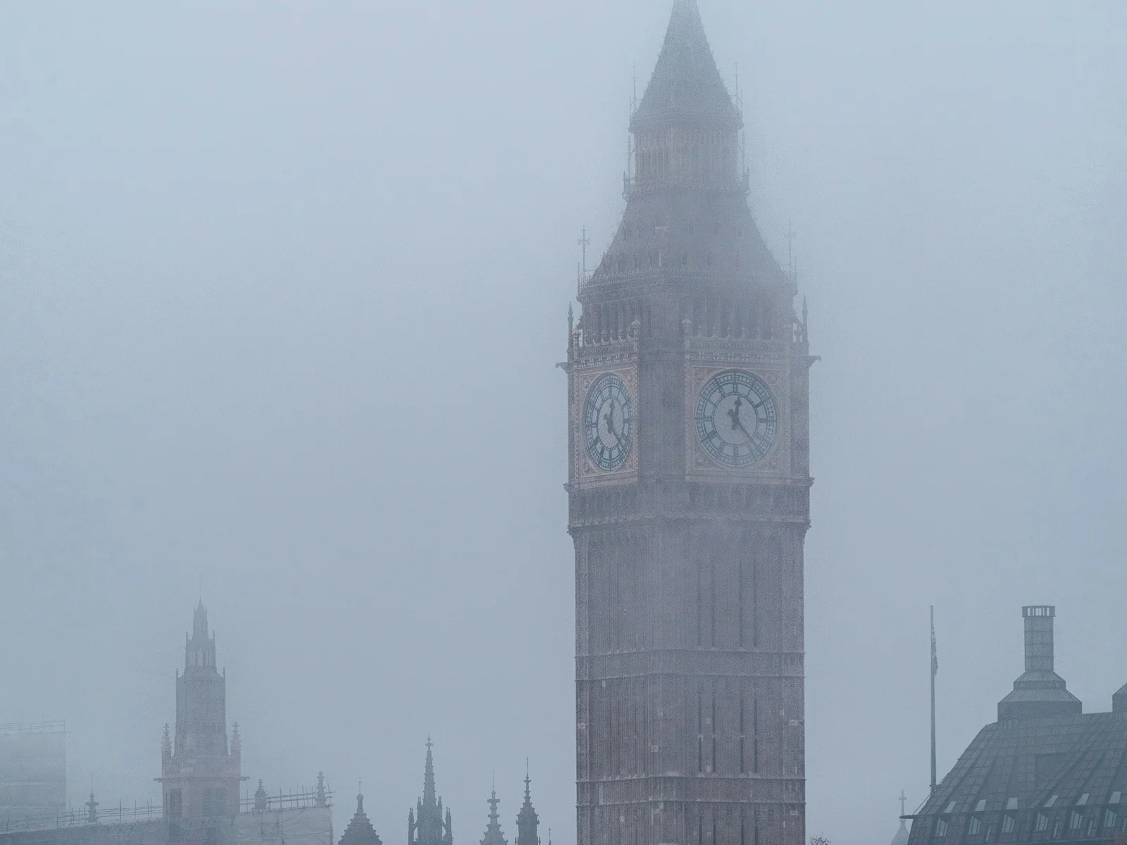 Elizabeth Tower and the Palace of Westminster fading into thick fog over the Thames