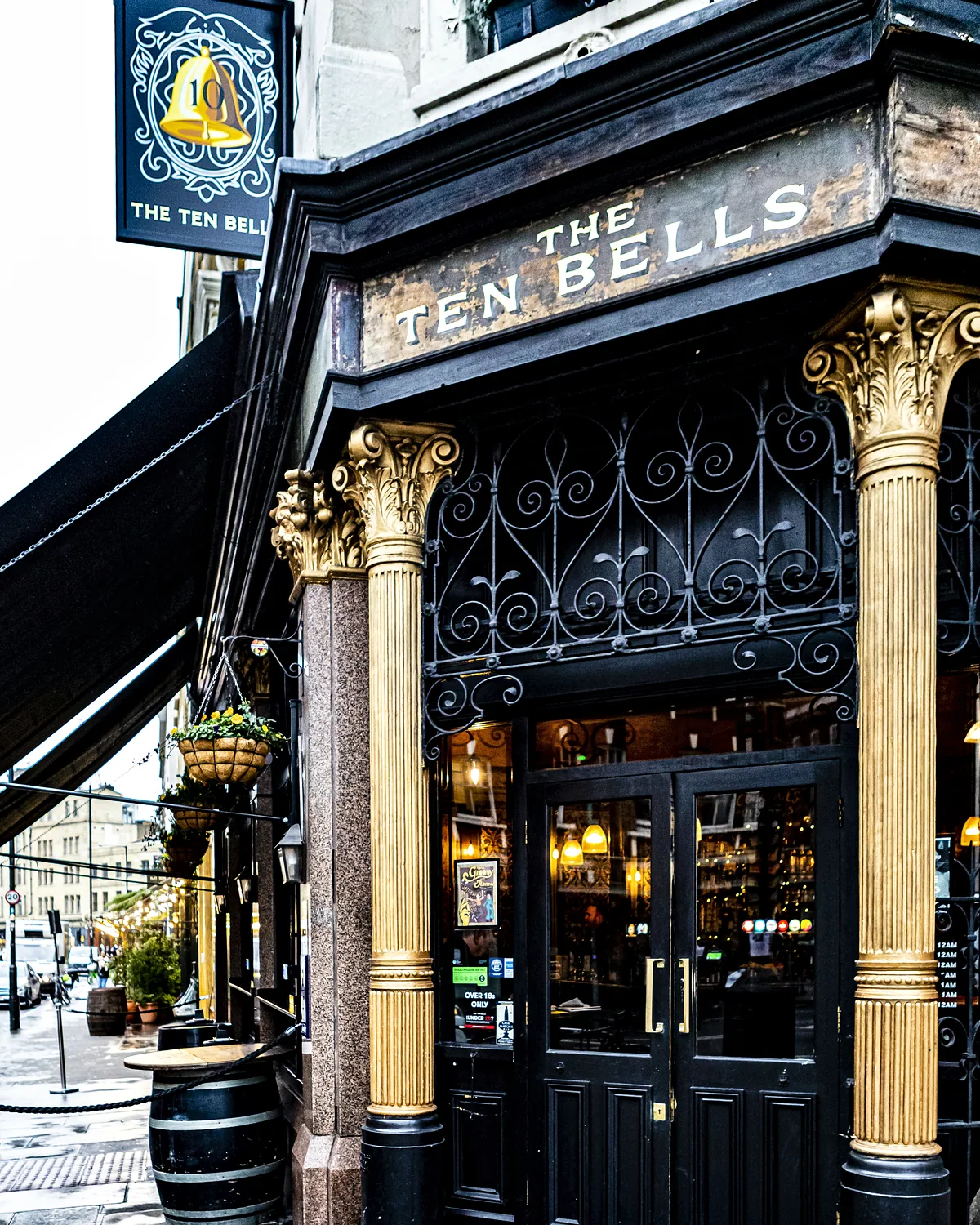 The black and gold Victorian frontage of The Ten Bells pub with its hanging bell sign