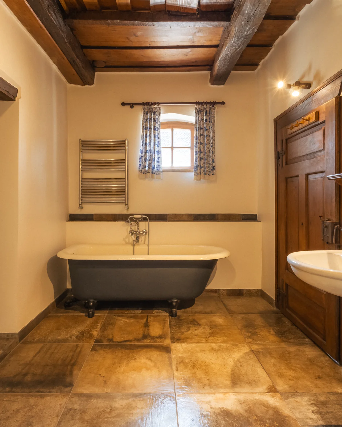 The Prince's Suite bathroom, with a freestanding bathtub, a small window and a washbasin under a mirror