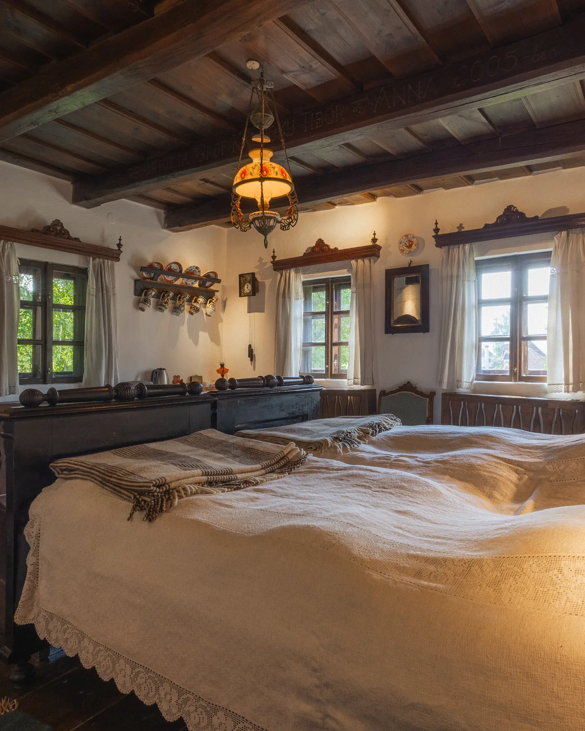 Uncle Imre's room, with a wooden bed under a woven blanket, antique cabinets and a beamed ceiling