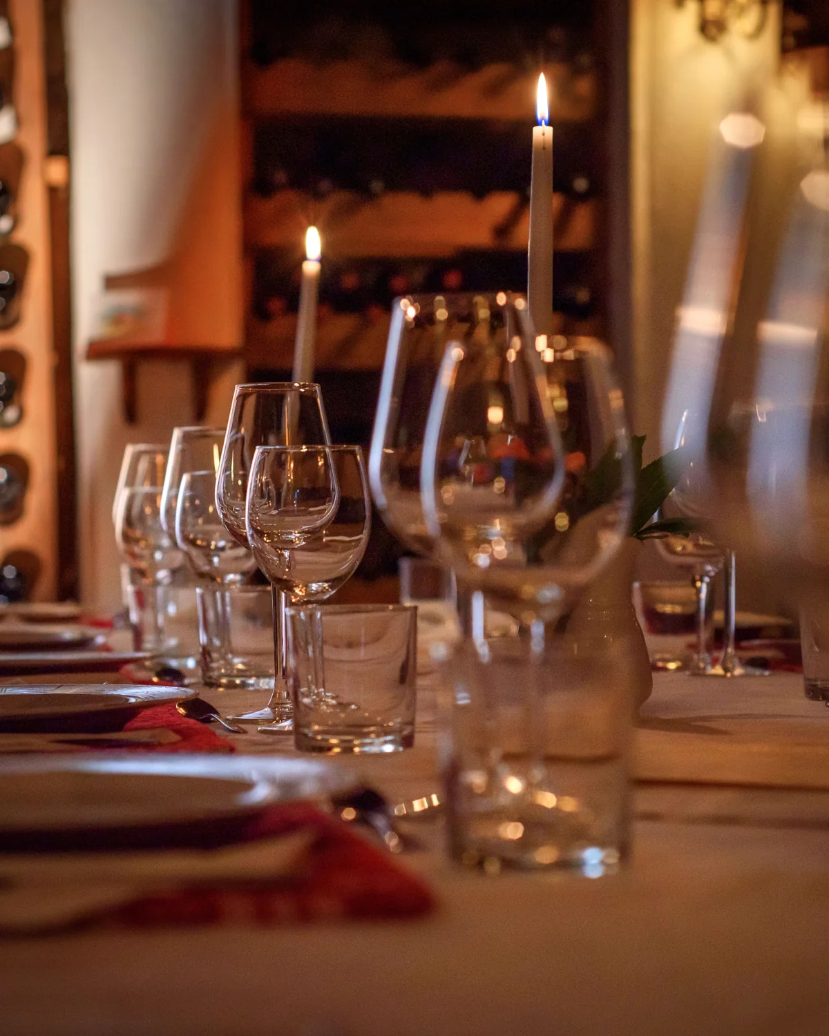 Candles and wine glasses on a table in the vaulted wine cellar of the main house