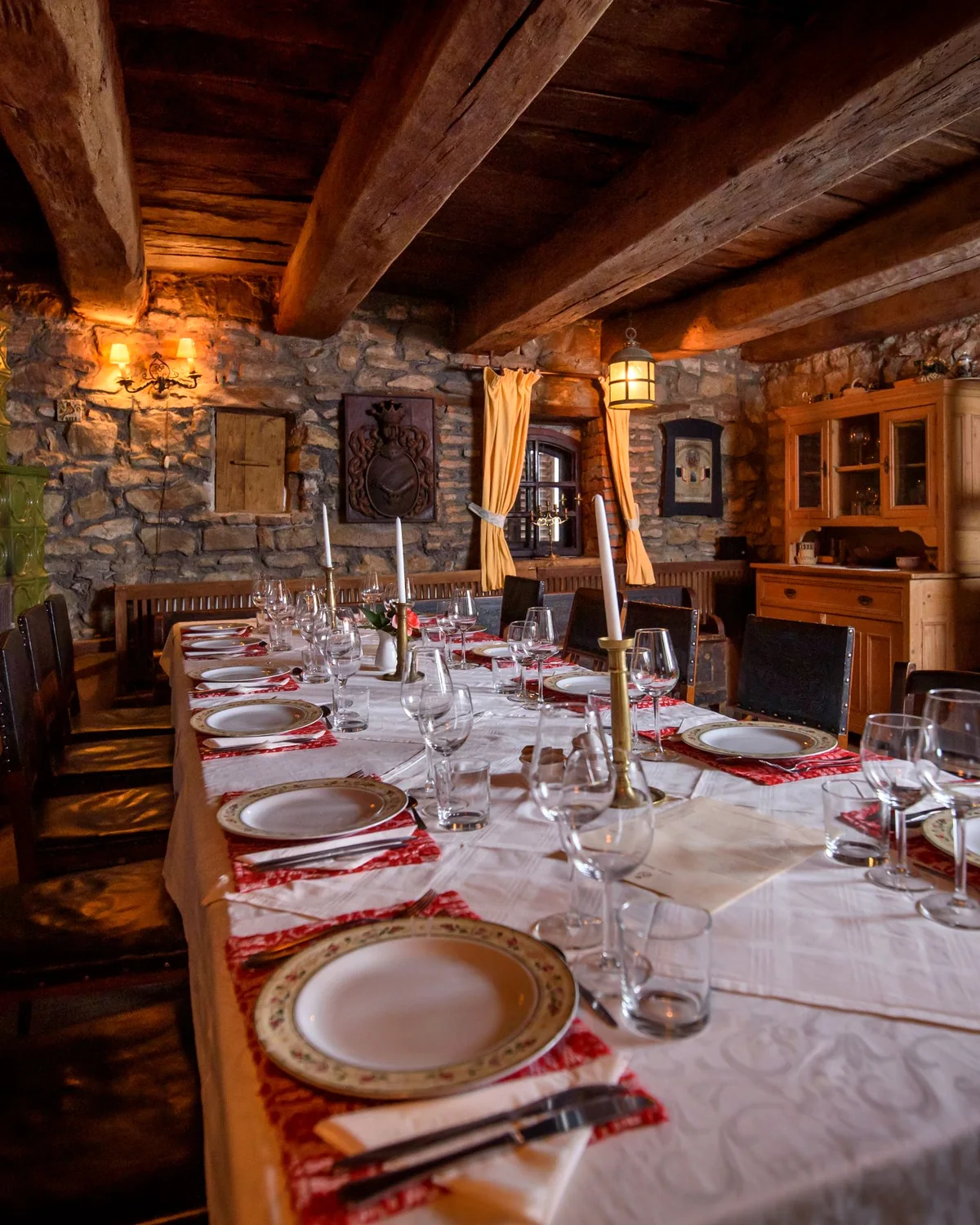 A long candlelit table set with plates and wine glasses under the stone vaults of the wine cellar