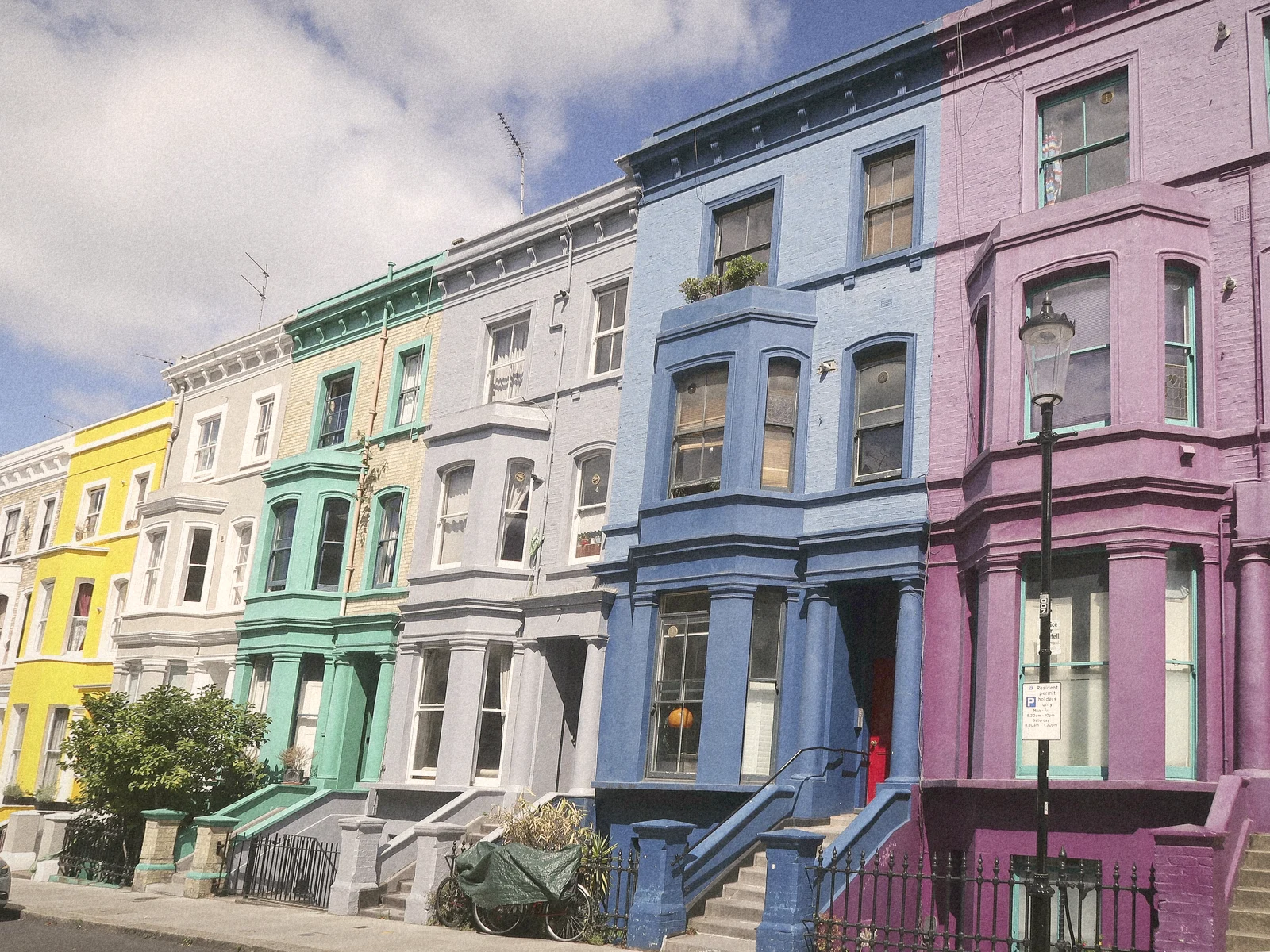 A row of pastel-painted Victorian houses on a Notting Hill street