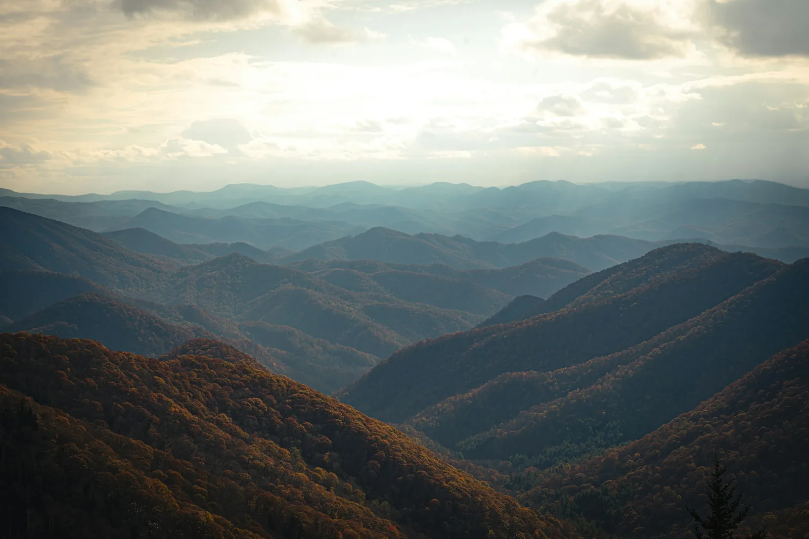 Layer upon layer of blue mountain ridges fading into a cloudy sky, seen from the Blue Ridge Parkway near Asheville