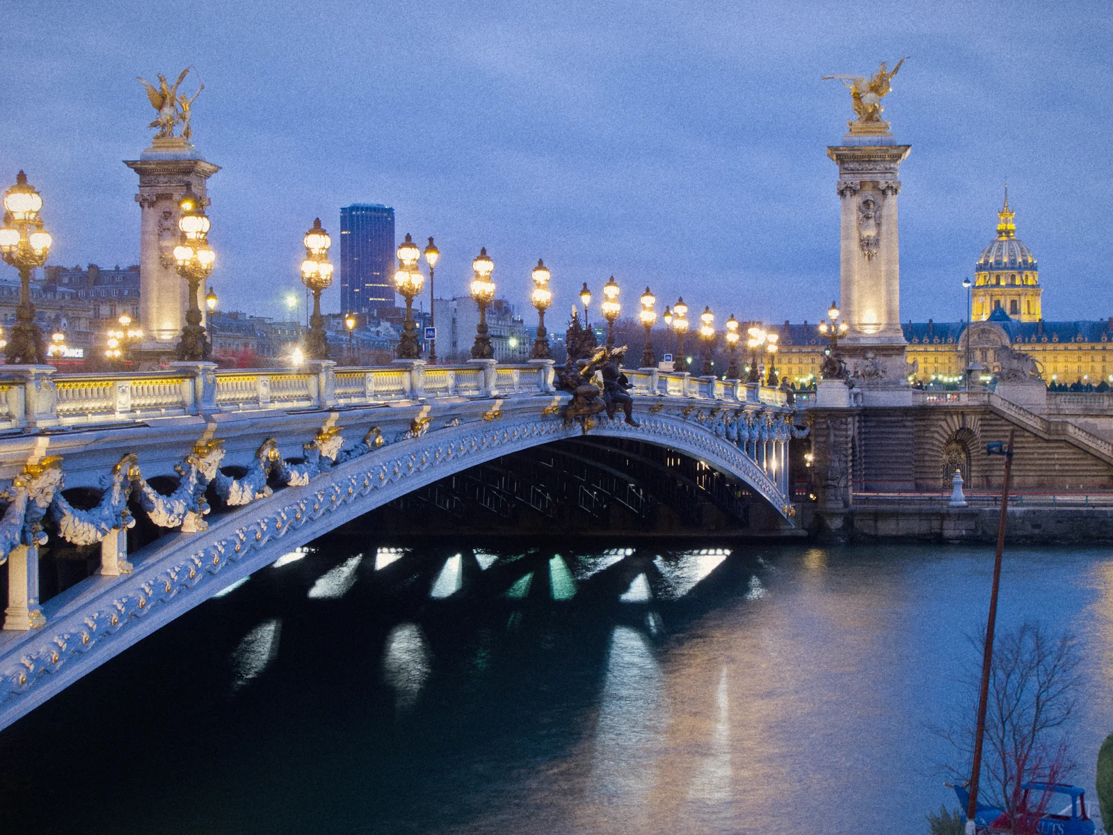 Pont Alexandre III and its gilded statues and lamps over the Seine at blue hour