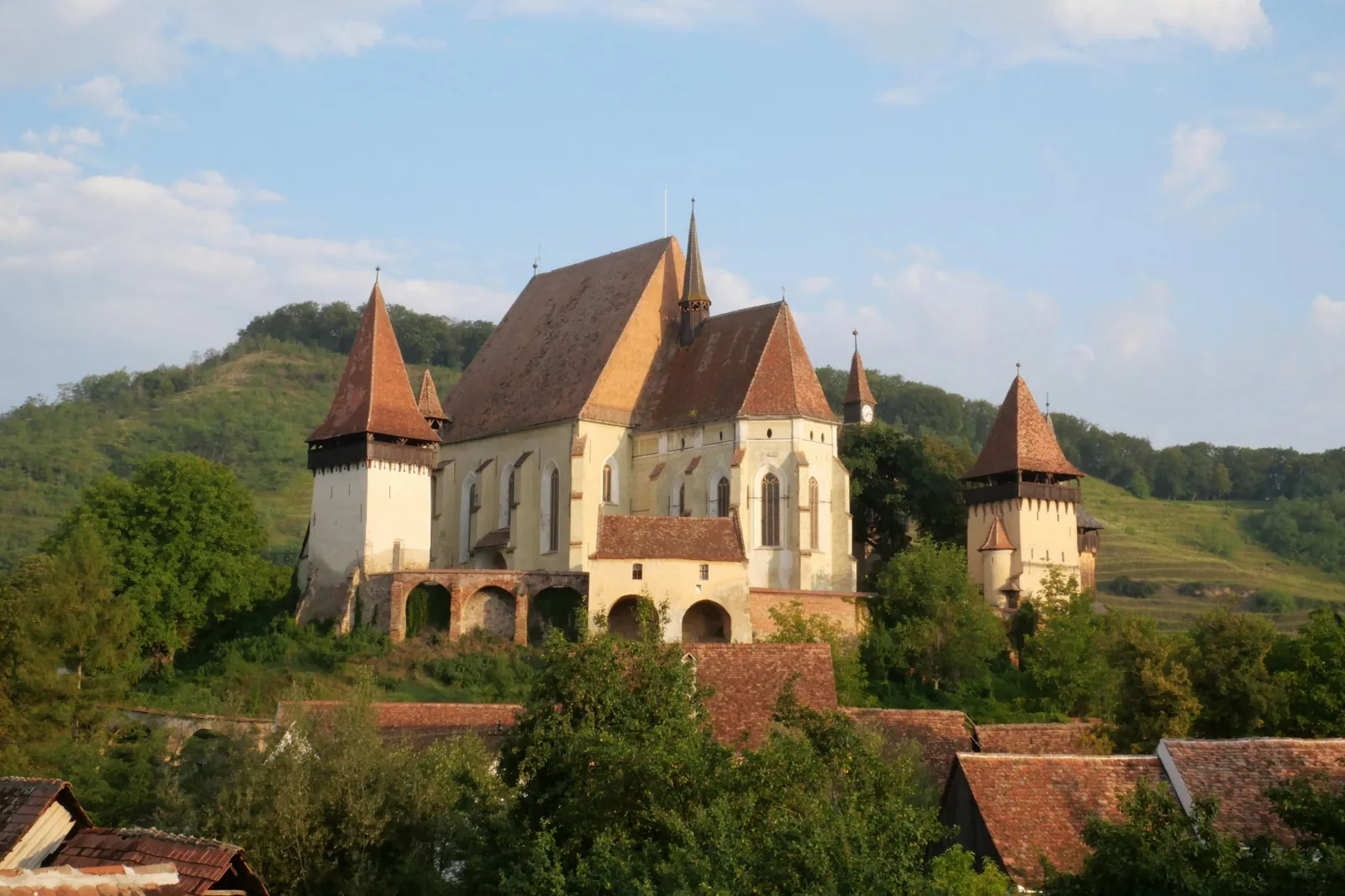 Biertan's fortified church with towers and defensive walls on a green hill above the village