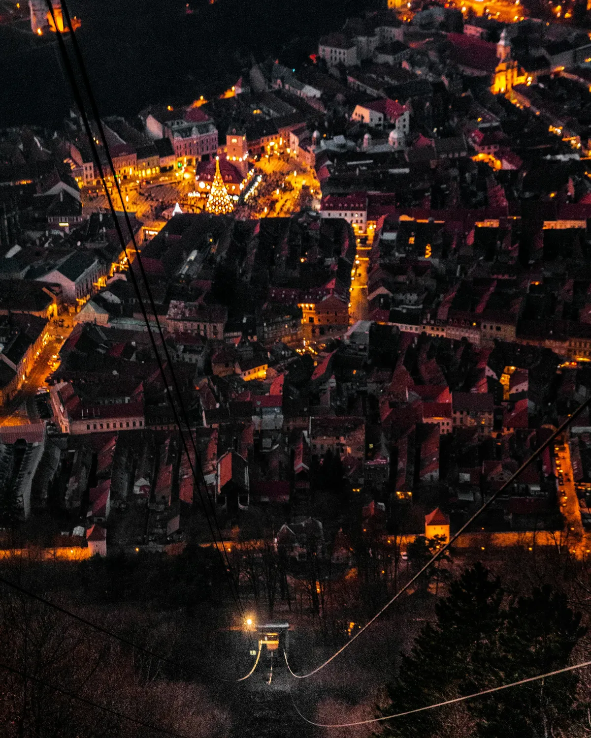 Brașov's old town glowing orange at night, seen from Tâmpa Mountain
