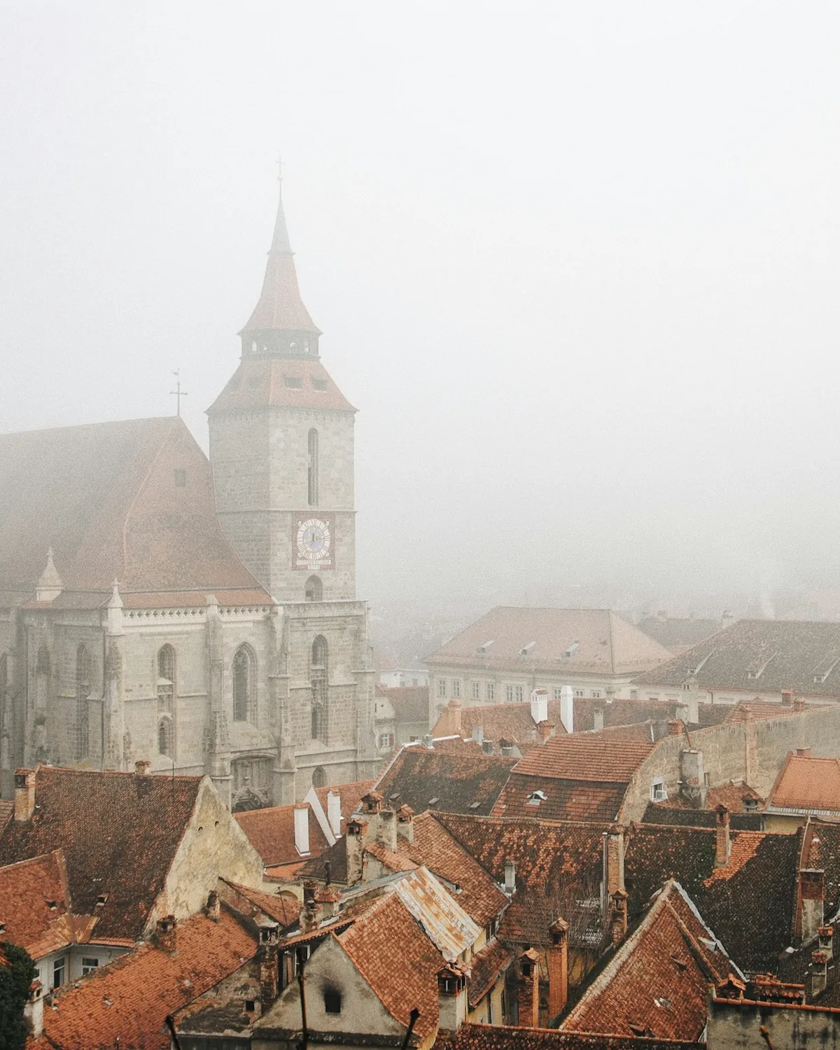 Brașov's Black Church and red rooftops fading into thick morning fog