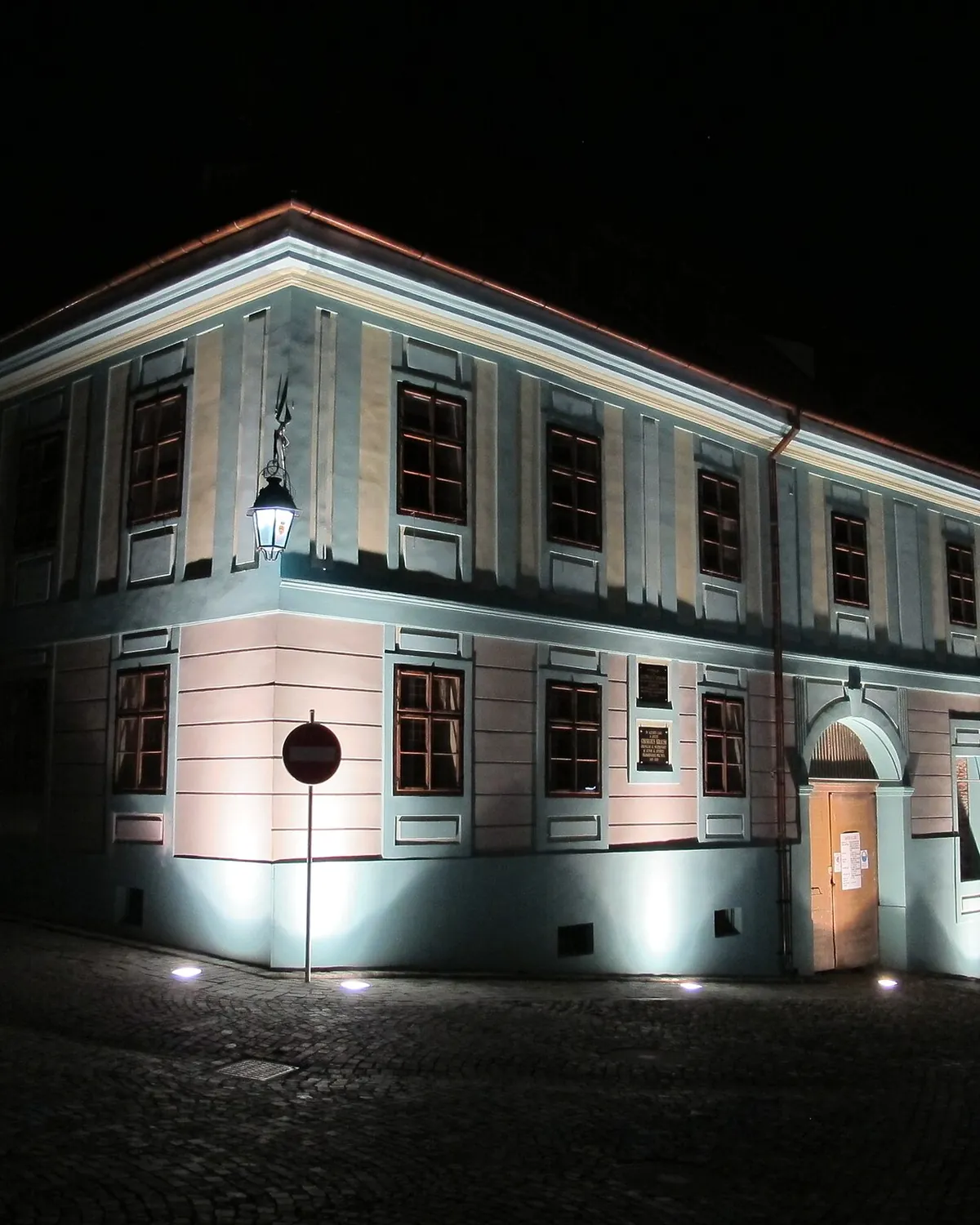 The white facade of Casa Georgius Krauss lit softly at night on a citadel street in Sighișoara