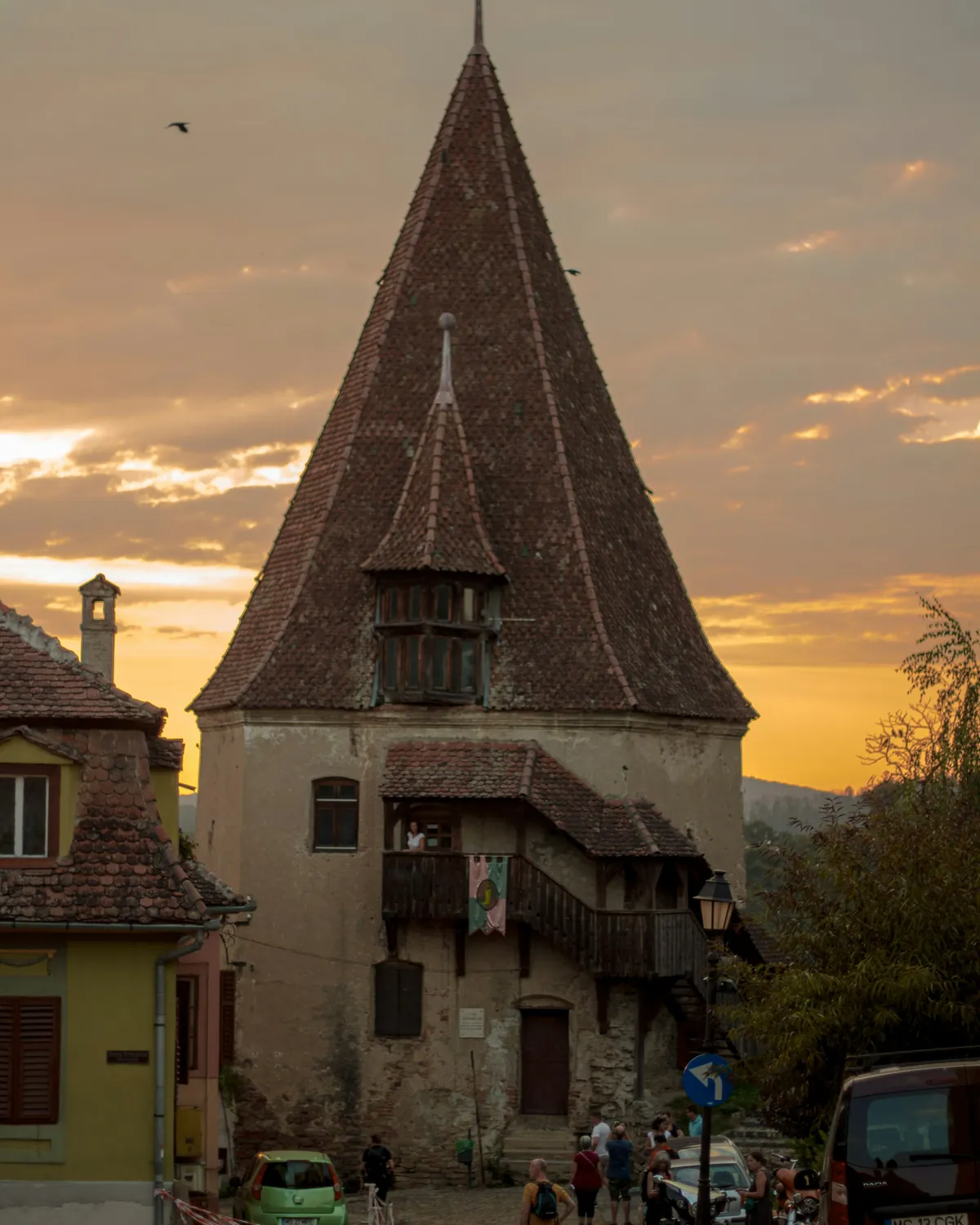 A steep-roofed medieval tower in Sighișoara against a warm dusk sky