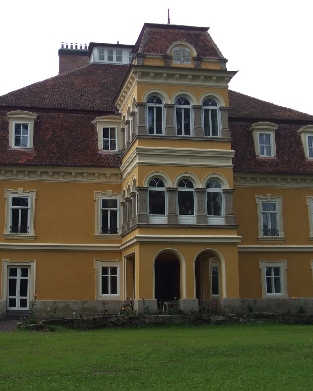 The ochre facade of the Mikes family castle at Zabola, with tall windows and a lawn