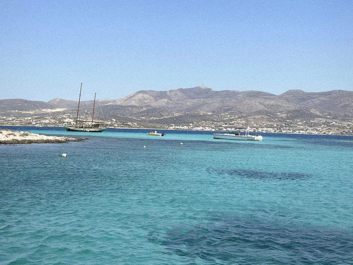 Turquoise water and anchored sailboats off Antiparos under a clear blue summer sky