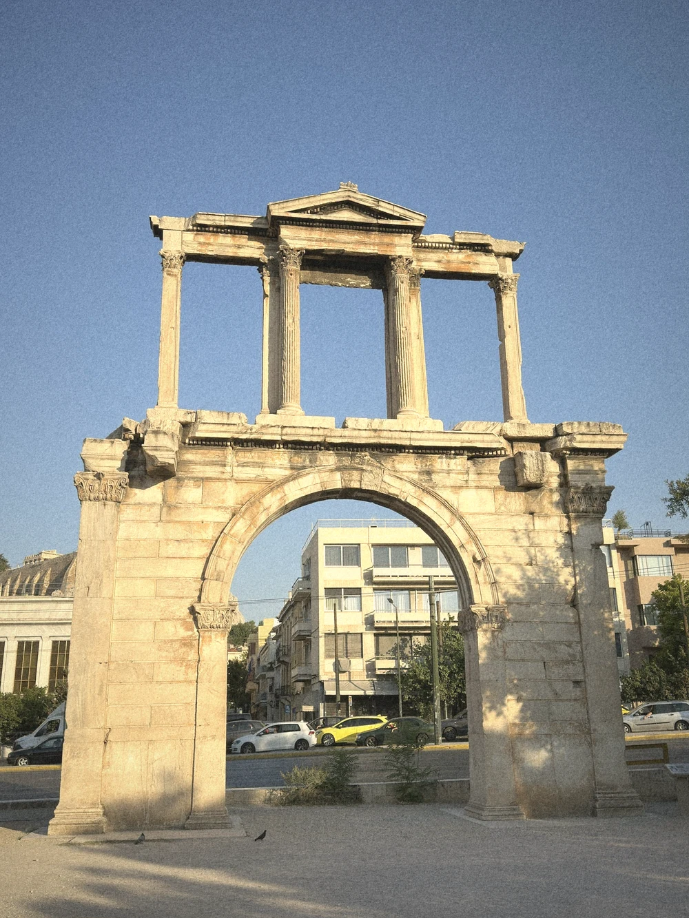 Hadrian's Arch, a weathered marble gateway with columns on top, glowing in late sun