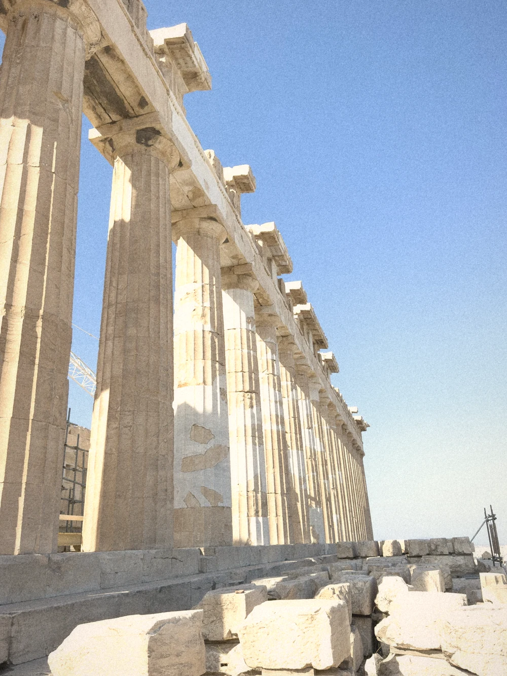 Looking up along the Parthenon's huge Doric columns against a deep blue sky