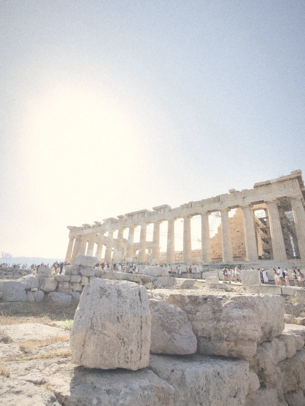The Parthenon in bright sunshine with marble blocks in the foreground
