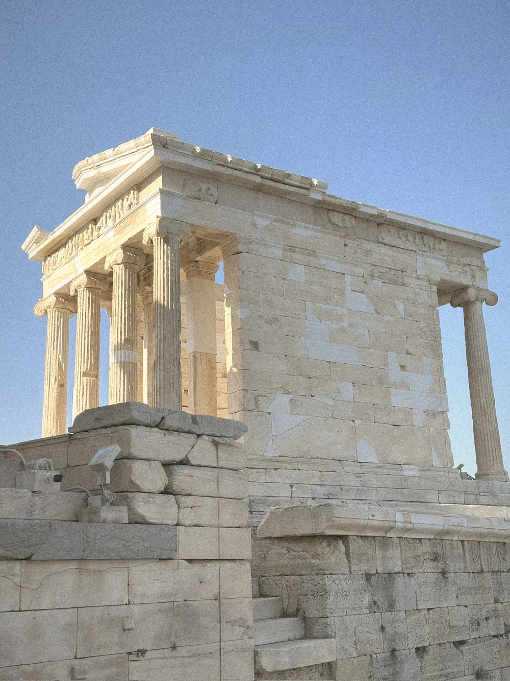 The small marble Temple of Athena Nike on a stone bastion under a blue sky