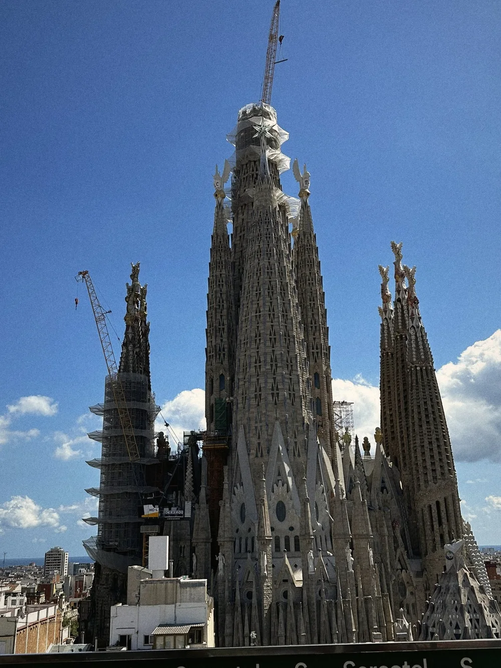 The spires of the Sagrada Família against a deep blue sky with white clouds