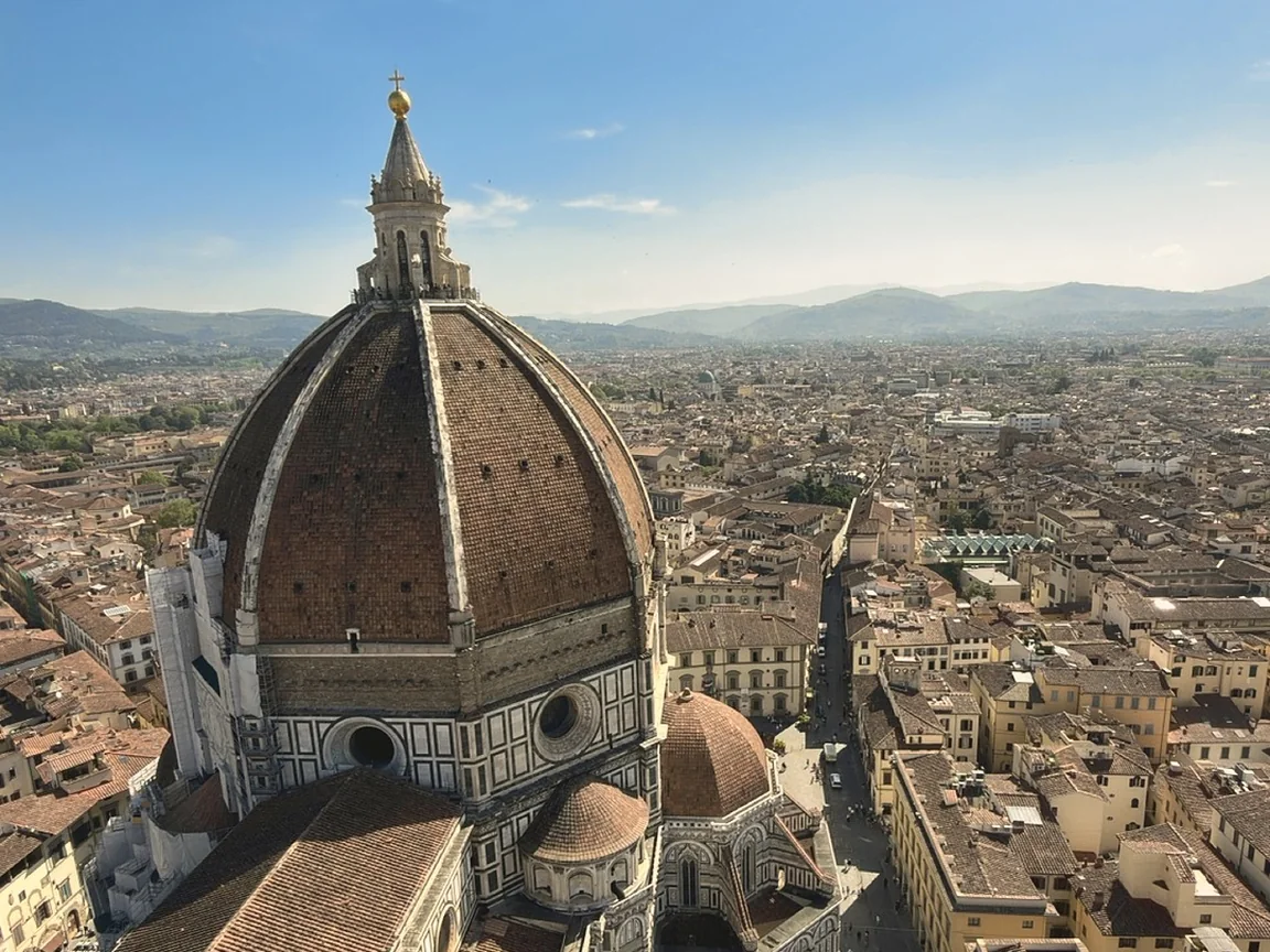 Brunelleschi's dome and the terracotta rooftops of Florence seen from the top of Giotto's bell tower under a blue sky