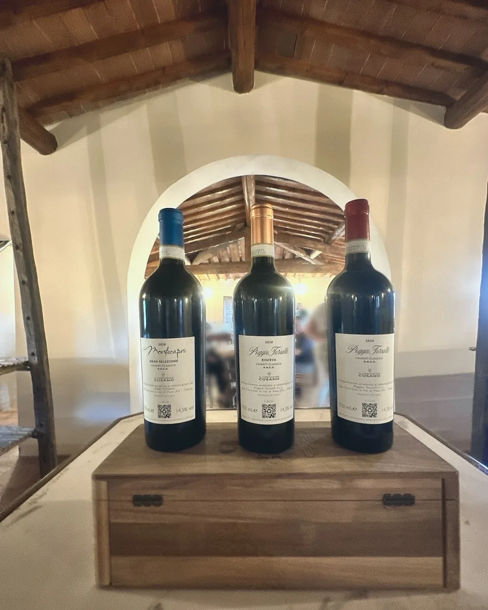 Three bottles of Chianti Classico on a wooden box in a beamed tasting room