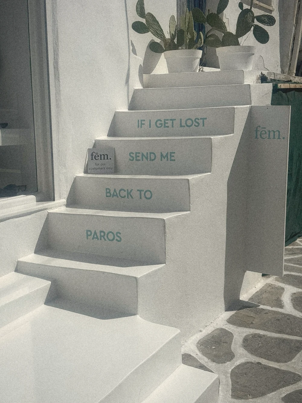 White stairs painted with the words If I get lost send me back to Paros