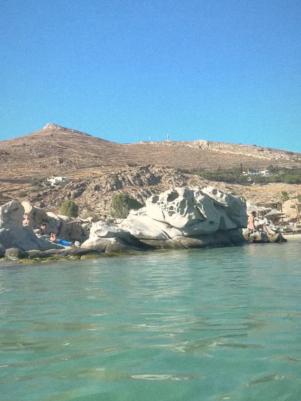 Swimming-level view of clear green water and the granite boulders of Kolymbithres