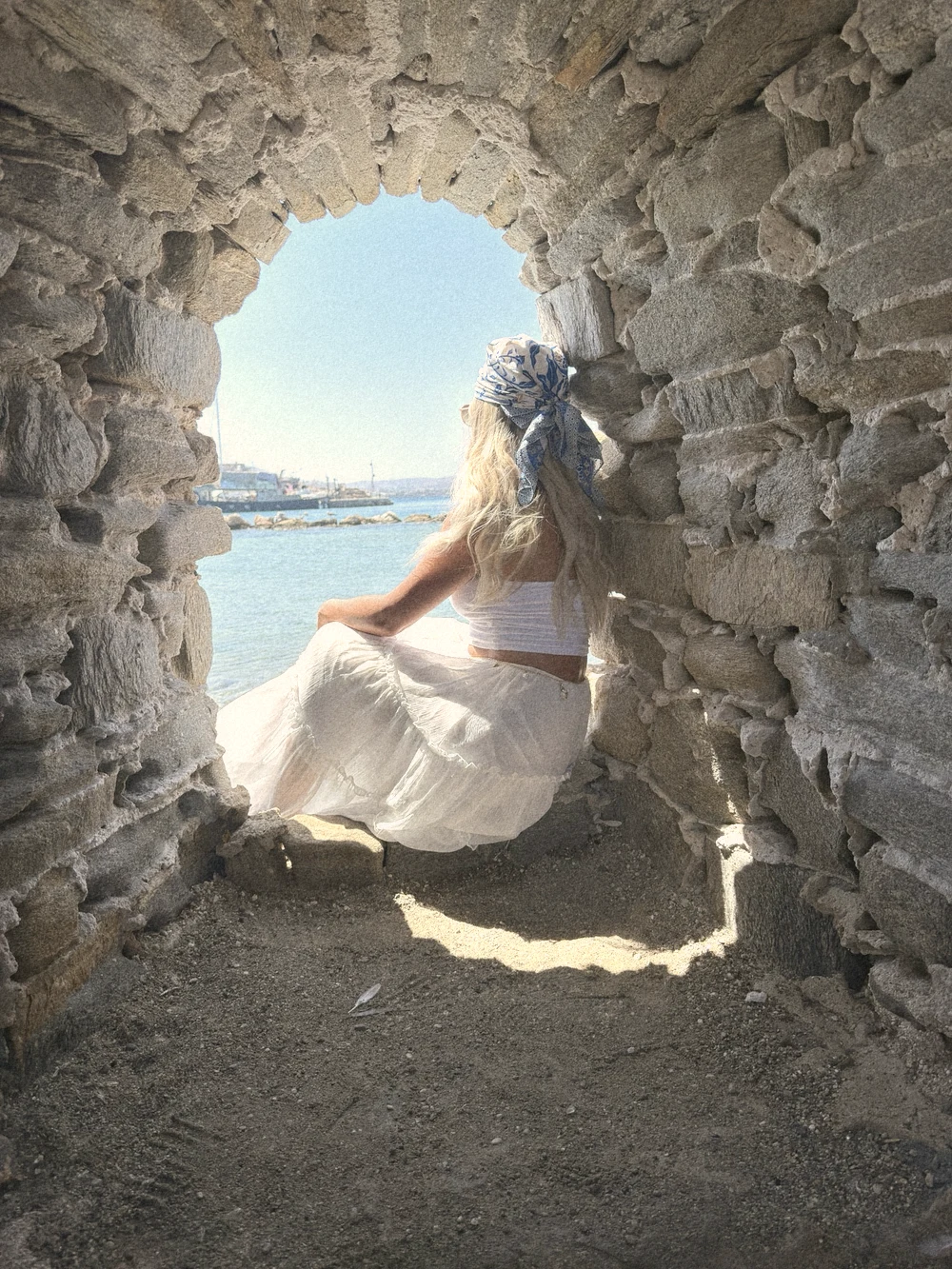 Sitting in a stone arch window of Naoussa's Venetian castle, looking out at a calm turquoise sea