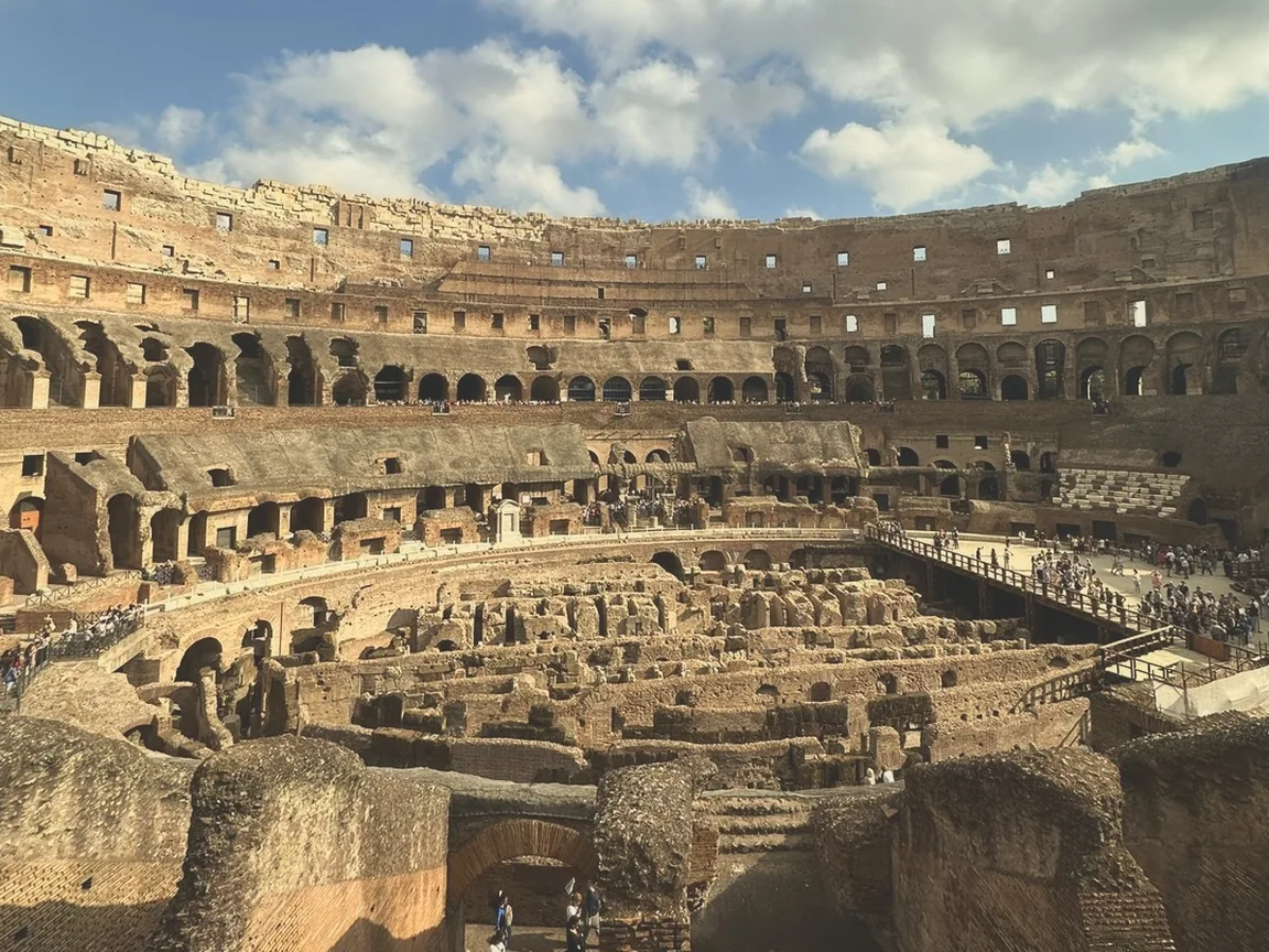 The tiers and underground passages inside the Colosseum under white clouds