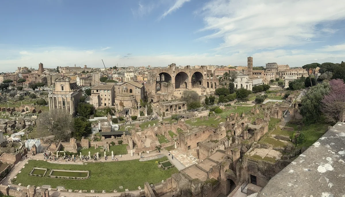 A wide view over the Roman Forum ruins and green lawns from the Palatine Hill