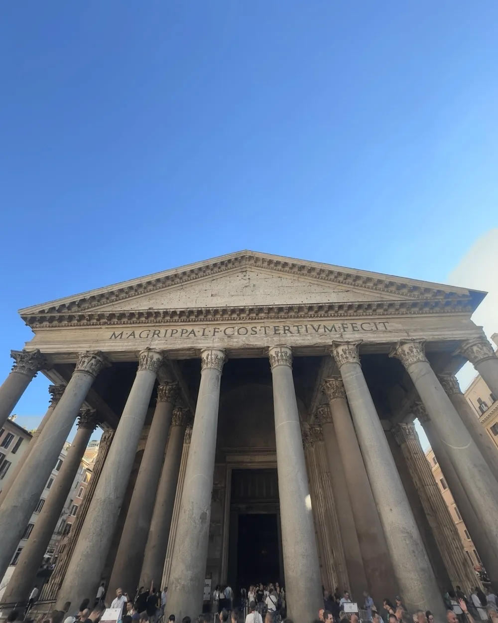 The columned portico of the Pantheon under a clear blue sky