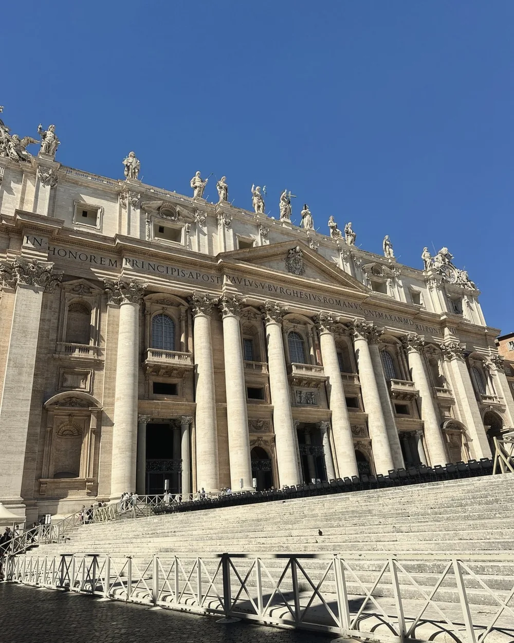The facade of St. Peter's Basilica and its statues against a deep blue sky