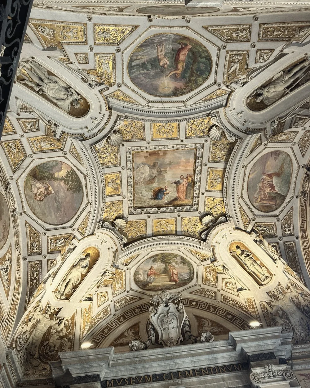 An ornate gilded ceiling with painted medallions in the Vatican Museums