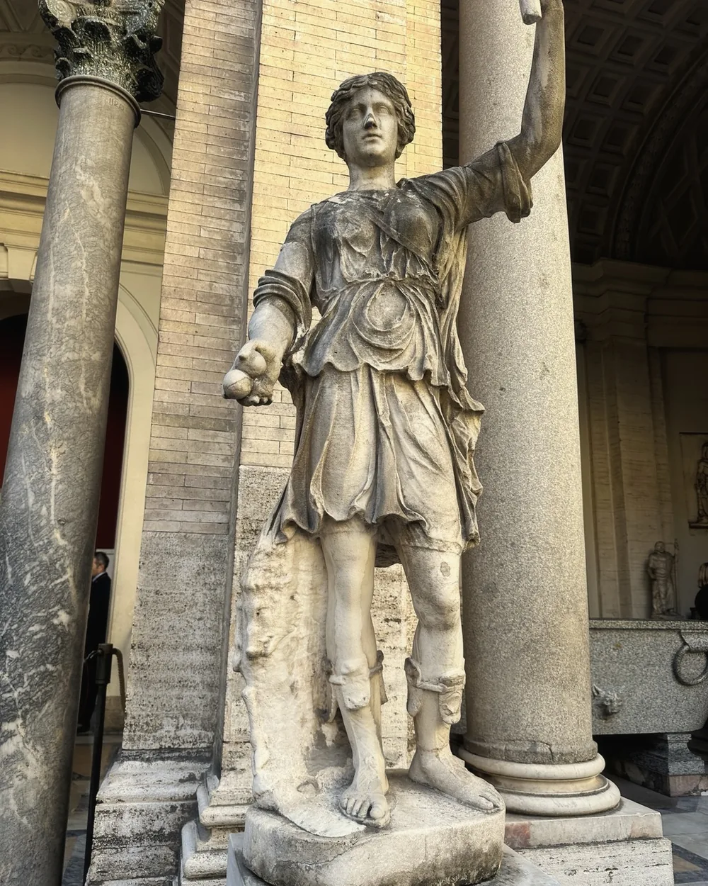 A classical marble statue between fluted columns in the Vatican Museums