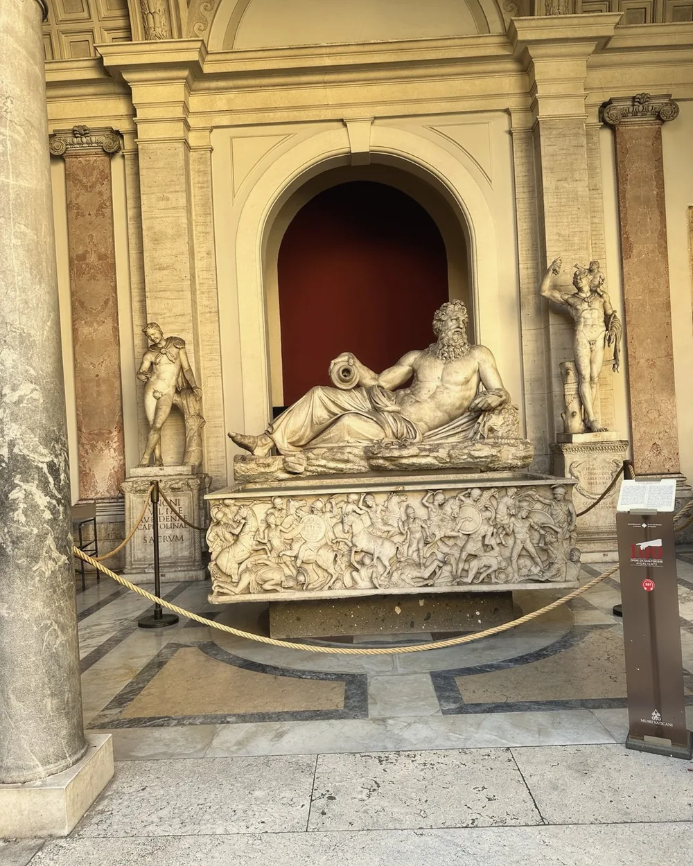A reclining river god sculpture in a niche in the Vatican Museums