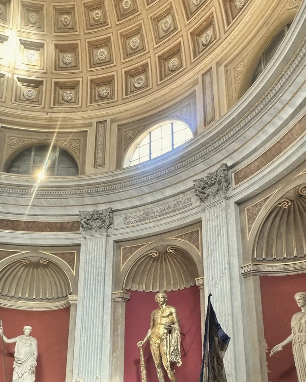 Colossal statues in red niches beneath the coffered dome of the Sala Rotonda