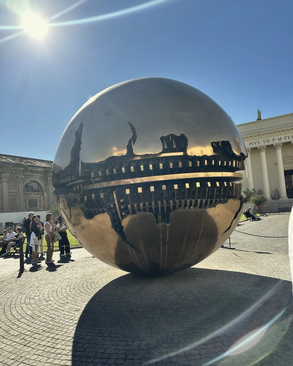 The bronze Sphere within Sphere sculpture reflecting the sky in the Cortile della Pigna