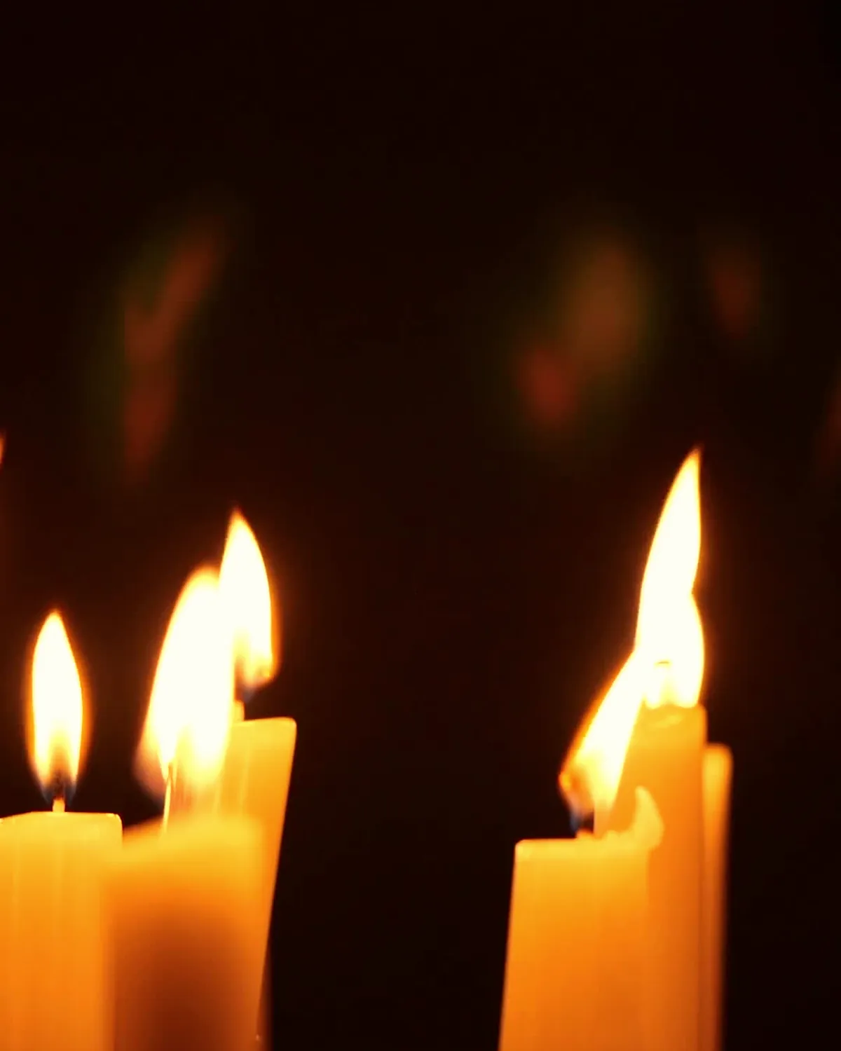 Candle flames glowing against a dark background