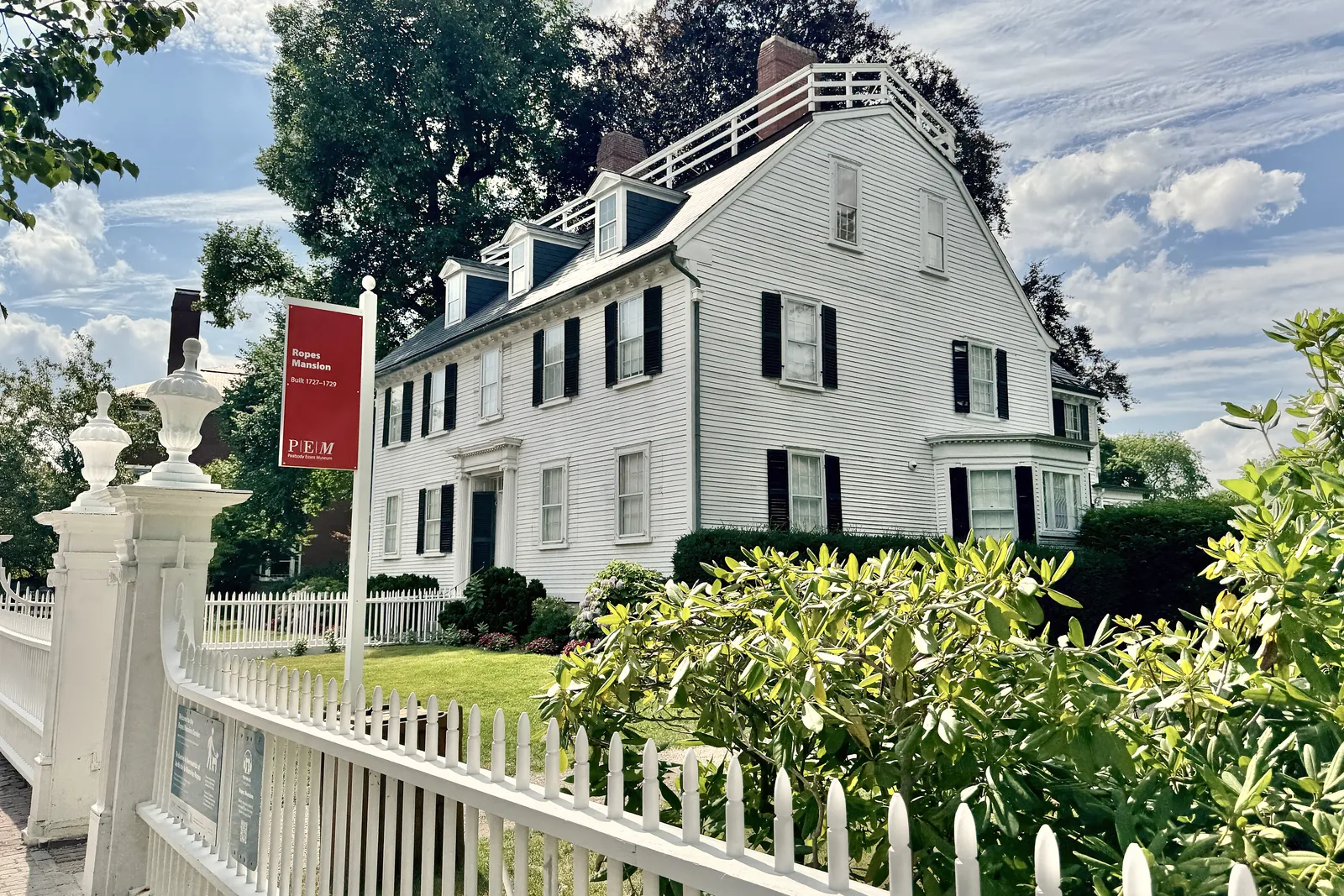 The white Ropes Mansion on Essex Street seen past its fence and garden greenery