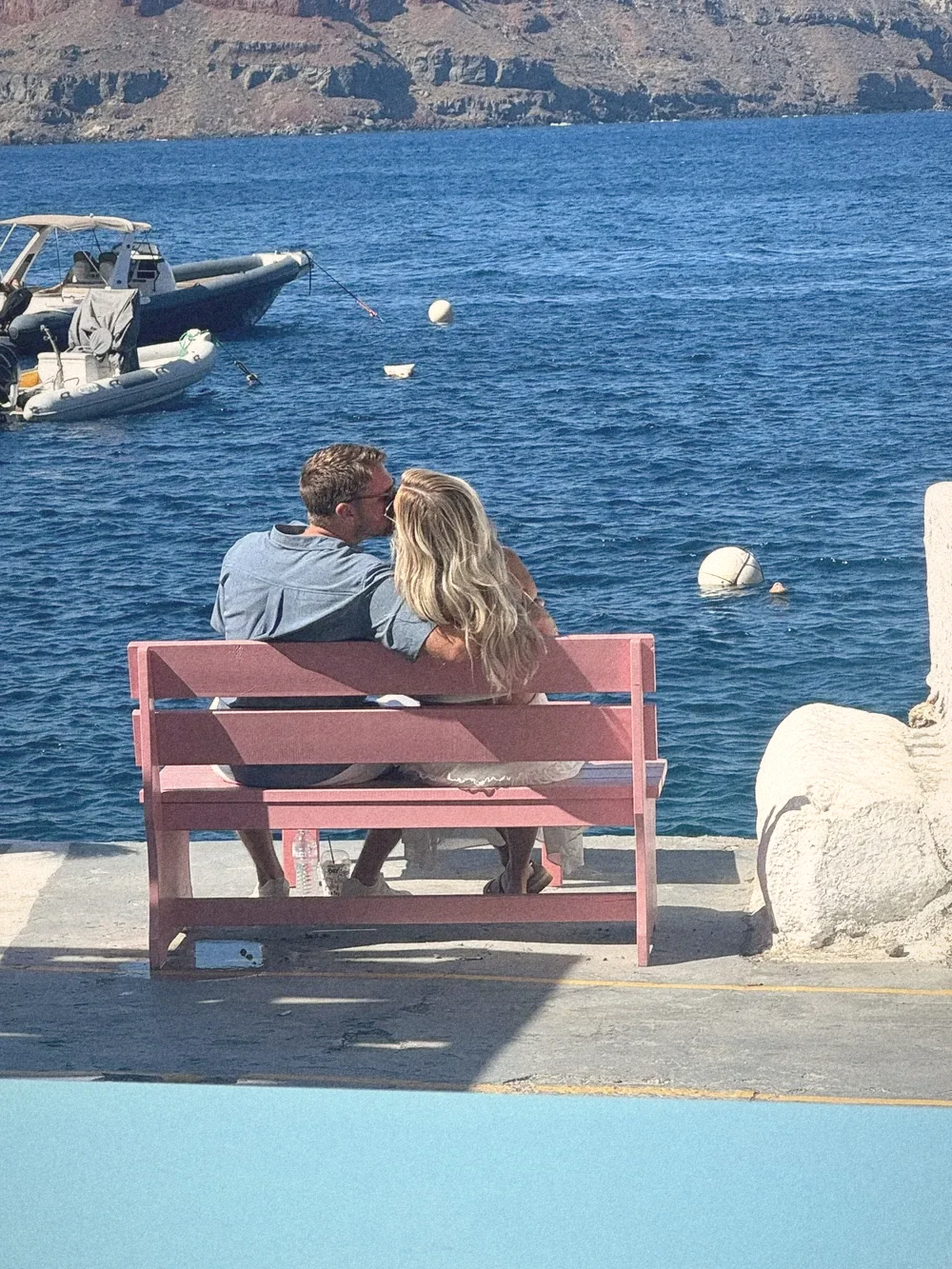 The two of us from behind on a pink bench at the water's edge in Amoudi Bay