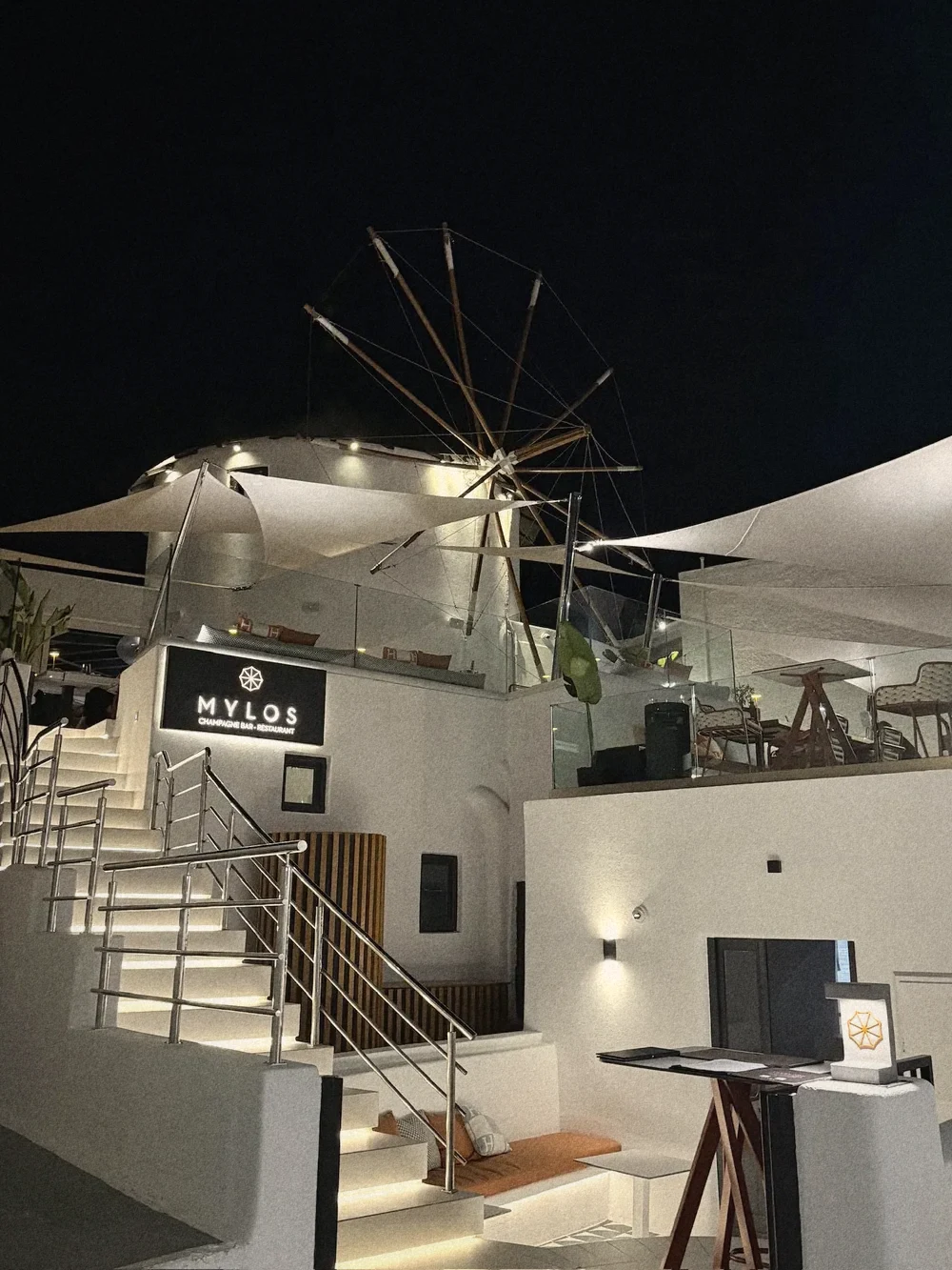 Mylos at night, with the lit-up windmill above white terraces and steps