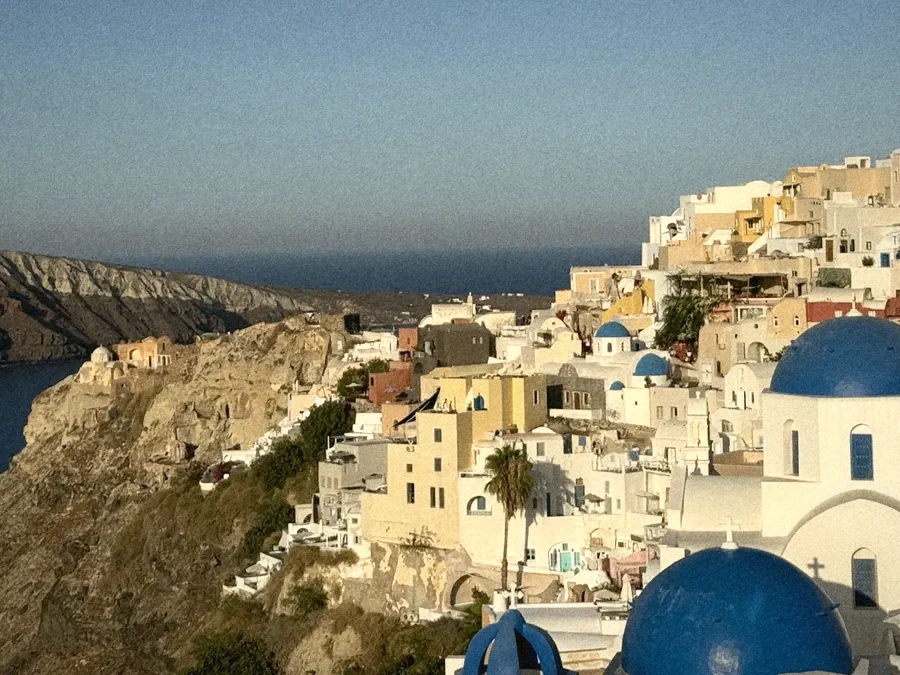 Oia's cliffside village with blue church domes above the caldera
