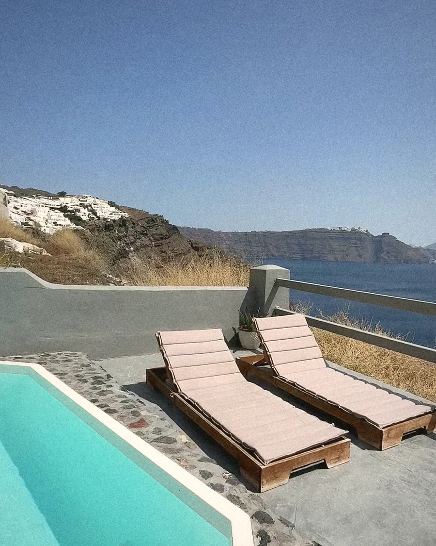 Two loungers on our pool terrace above the Santorini caldera, with the sea beyond